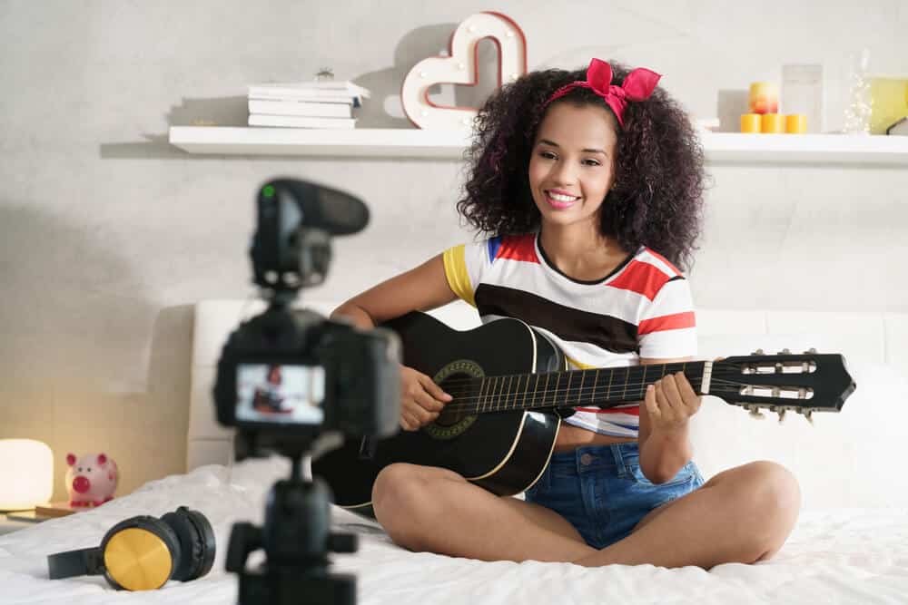 learn something new everyday by watching video tutorials on tv - actual image of girl videotaping a tutorial and teaching guitar