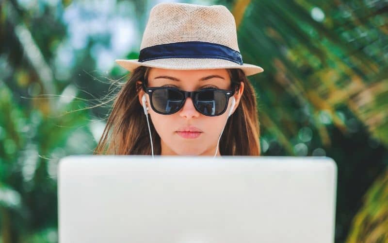 How to cowork remotely to get a higher paying job. Woman working outside remotely on her laptop.